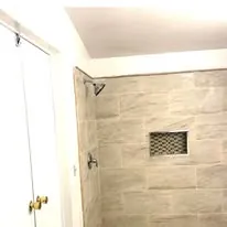Finished tile shower with a recessed niche and glass surround